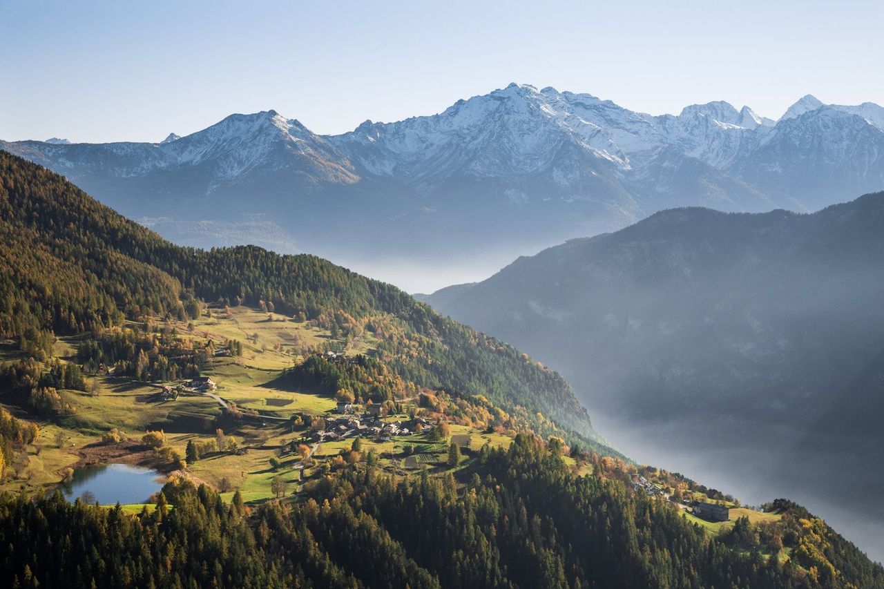 Autumn valley above Antey-Saint-André in Valle d’Aosta, with Lago di Lod, mist and snow-capped peaks